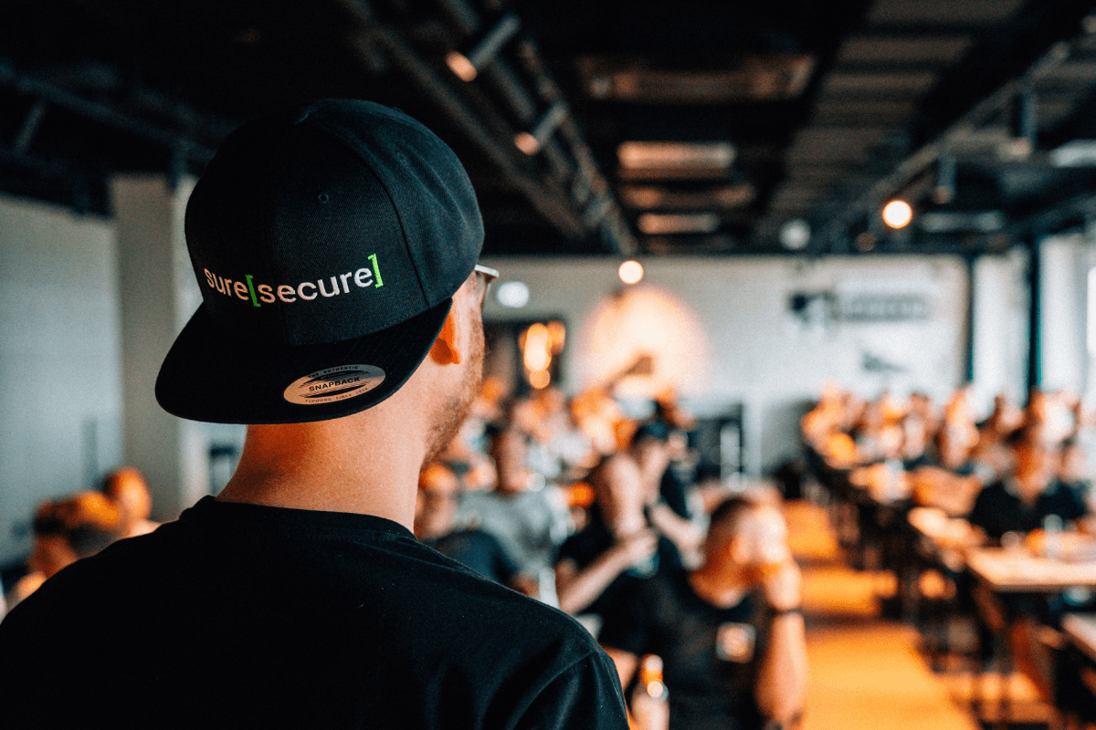 Speaker mit Suresecure Cap bei einem Cybersecurity-Workshop vor Publikum – IT-Event mit Fokus auf Security, Awareness und Weiterbildung.
