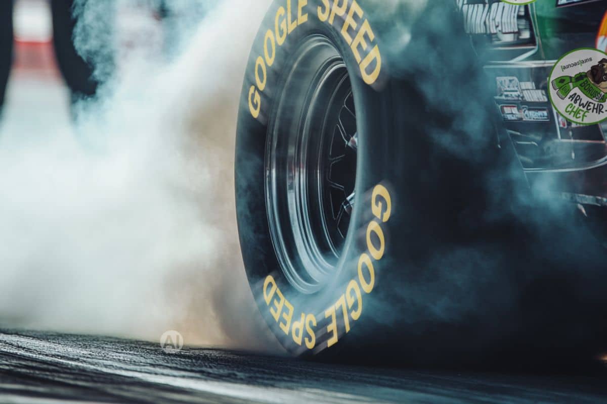 Nahaufnahme eines Rennreifens beim Burnout auf einer Rennstrecke – starke Rauchentwicklung durch hohe Geschwindigkeit und maximale Performance im Motorsport.