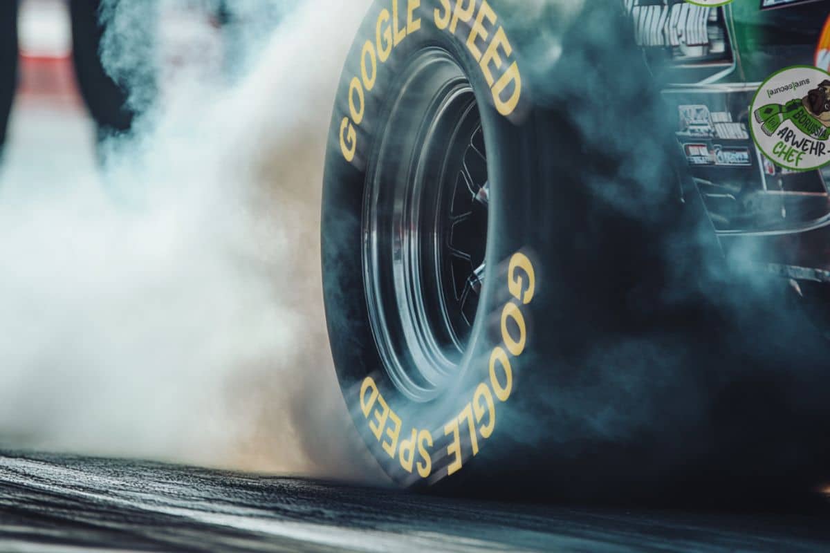 Nahaufnahme eines Rennreifens beim Burnout auf einer Rennstrecke – starke Rauchentwicklung durch hohe Geschwindigkeit und maximale Performance im Motorsport.